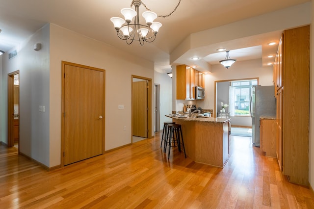 2230 Lower Afton Rd E, Saint Paul, MN 55119 - kitchen featuring appliances with stainless steel finishes, light wood-type flooring, brown cabinets, and a peninsula