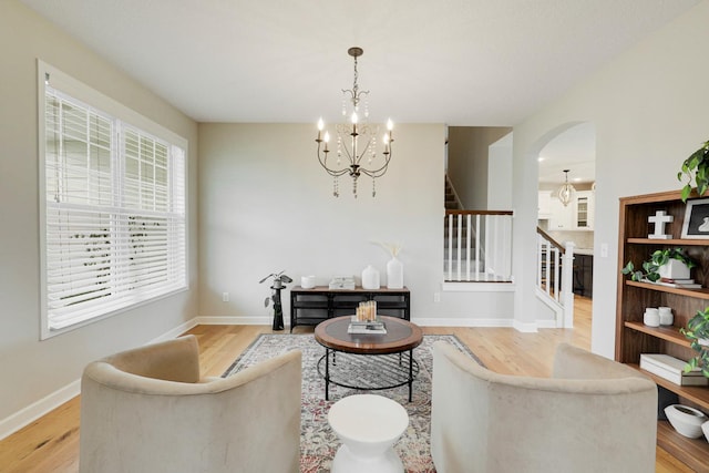 8633 Ambergate Dr, Victoria, MN 55386 - living room with stairway, a chandelier, light wood finished floors, and arched walkways