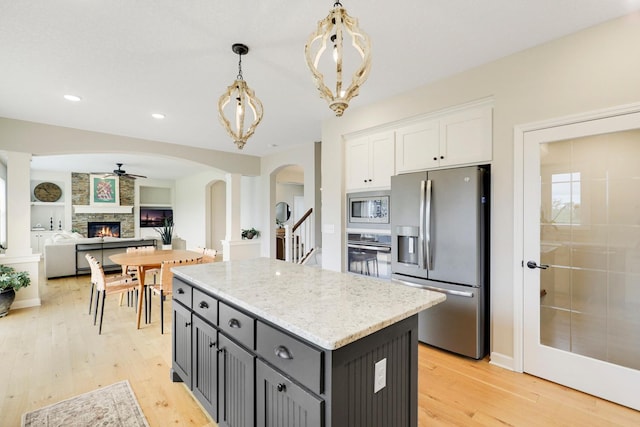 8633 Ambergate Dr, Victoria, MN 55386 - kitchen with appliances with stainless steel finishes, white cabinetry, arched walkways, a center island, and light wood finished floors