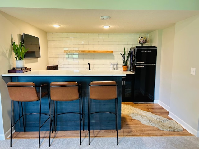 8633 Ambergate Dr, Victoria, MN 55386 - kitchen with freestanding refrigerator, a kitchen breakfast bar, light wood-style floors, tasteful backsplash, and light countertops