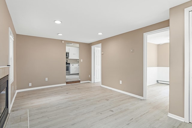 753 8th Ave S, Hopkins, MN 55343 - unfurnished living room featuring a baseboard radiator, a glass covered fireplace, light wood finished floors, recessed lighting, and baseboards