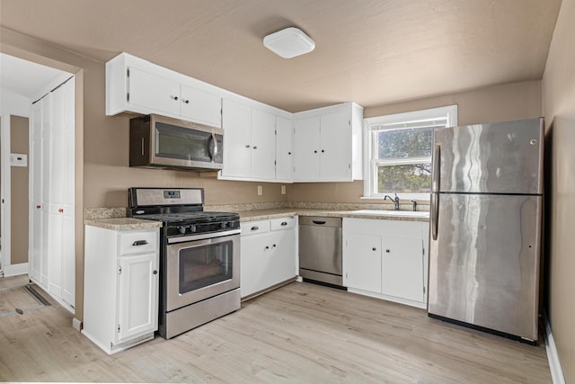 753 8th Ave S, Hopkins, MN 55343 - kitchen with appliances with stainless steel finishes, a sink, light wood-style floors, and white cabinets