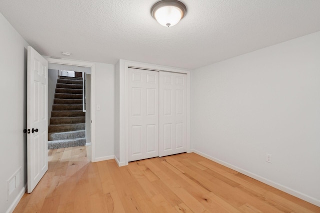 5110 Woodridge Rd, Minnetonka, MN 55345 - unfurnished bedroom featuring light wood finished floors, a textured ceiling, baseboards, and a closet