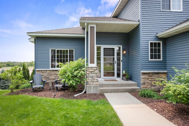 231 Winkler Trl, Cologne, MN 55322 - view of exterior entry with stone siding, a lawn, and a shingled roof