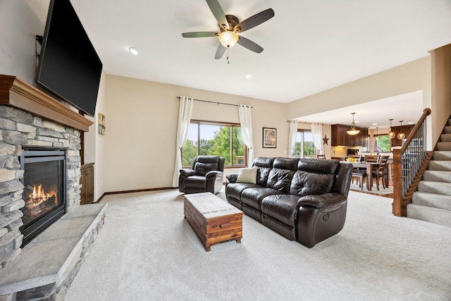 231 Winkler Trl, Cologne, MN 55322 - living room featuring stairway, a ceiling fan, a stone fireplace, light colored carpet, and baseboards