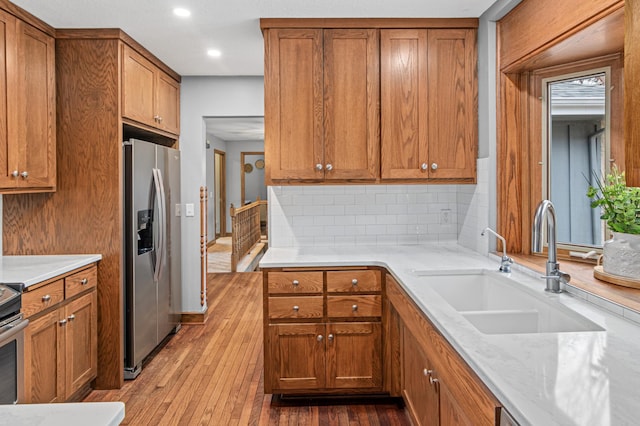 6230 Elm Ridge Cir, Corcoran, MN 55340 - kitchen featuring stainless steel fridge with ice dispenser, a sink, brown cabinetry, hardwood / wood-style floors, and tasteful backsplash