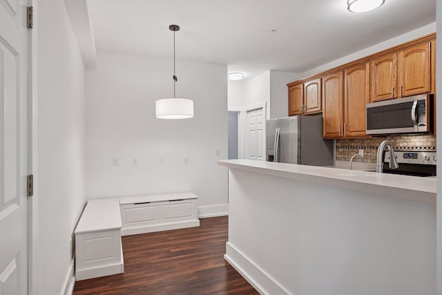 1924 Shamrock Pl, Chaska, MN 55318 - kitchen featuring stainless steel appliances, tasteful backsplash, dark wood-style floors, decorative light fixtures, and brown cabinets