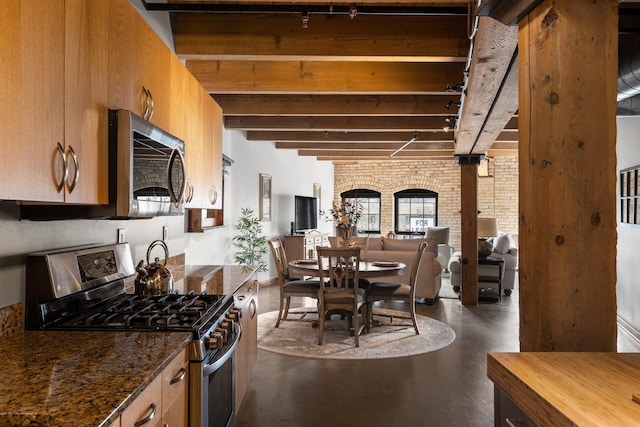404 Washington Ave N Unit 504, Minneapolis, MN 55401 - kitchen featuring stainless steel appliances, beamed ceiling, finished concrete floors, brown cabinets, and dark stone counters