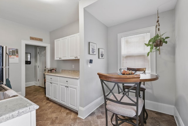 3314 Aldrich Ave N, Minneapolis, MN 55412 - kitchen with baseboards, white cabinetry, stone finish floors, and light countertops