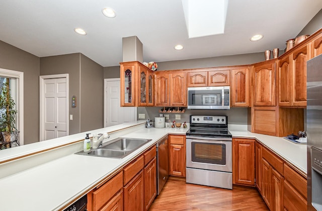706 Pershing Ave N, New Prague, MN 56071 - kitchen with stainless steel appliances, a sink, light wood-type flooring, glass insert cabinets, and brown cabinets