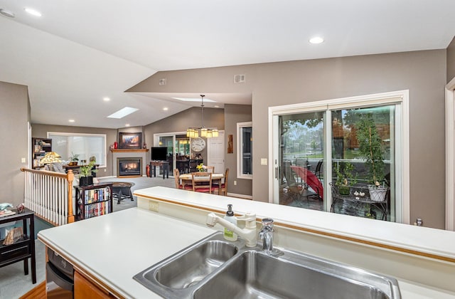 706 Pershing Ave N, New Prague, MN 56071 - kitchen with a glass covered fireplace, a sink, vaulted ceiling, open floor plan, and light countertops