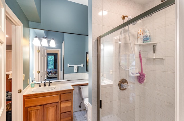 706 Pershing Ave N, New Prague, MN 56071 - ensuite bathroom with vanity, a stall shower, toilet, tile patterned floors, and tile walls