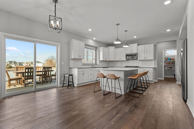 12946 Jewell Cir, Blaine, MN 55449 - kitchen with stainless steel appliances, a center island, a sink, dark wood finished floors, and recessed lighting