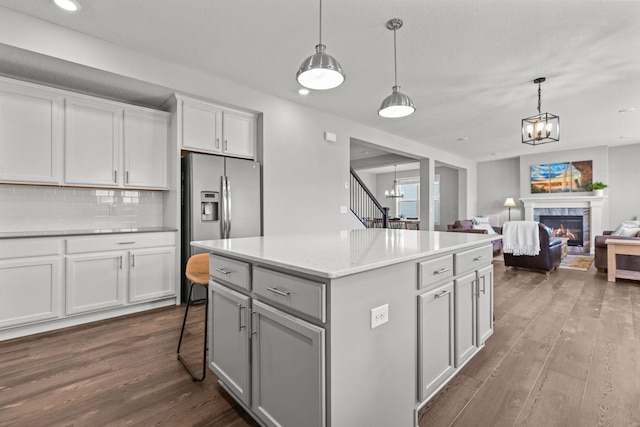 12946 Jewell Cir, Blaine, MN 55449 - kitchen with a chandelier, stainless steel fridge, dark wood-style floors, a kitchen island, and decorative backsplash