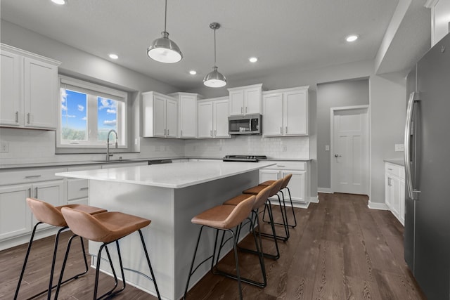 12946 Jewell Cir, Blaine, MN 55449 - kitchen with stainless steel appliances, a sink, a kitchen breakfast bar, a kitchen island, and white cabinets