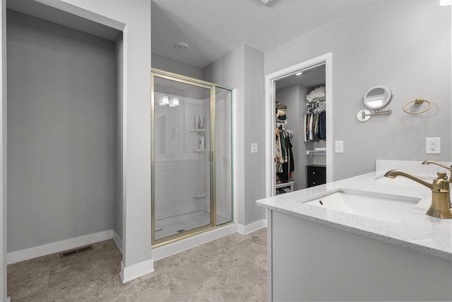 12946 Jewell Cir, Blaine, MN 55449 - full bath featuring a shower stall, a walk in closet, vanity, baseboards, and a textured ceiling
