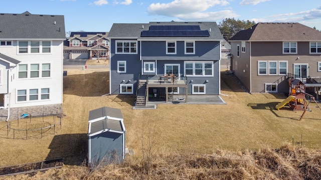 12946 Jewell Cir, Blaine, MN 55449 - rear view of house with a residential view, a patio area, solar panels, a playground, and a yard