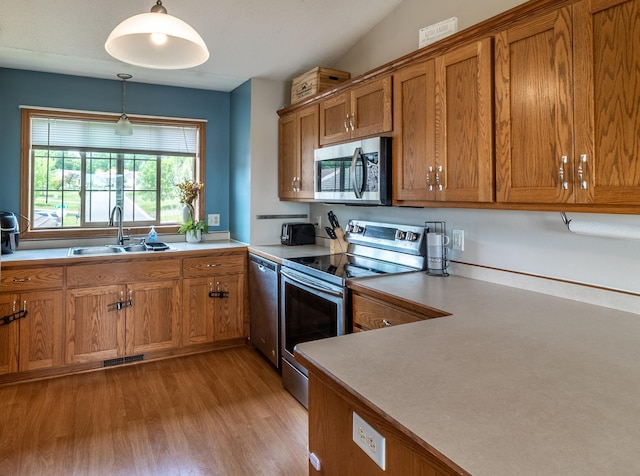 250 18th Ave SE, Saint Joseph, MN 56374 - kitchen with stainless steel appliances, a sink, brown cabinetry, light wood-type flooring, and hanging light fixtures