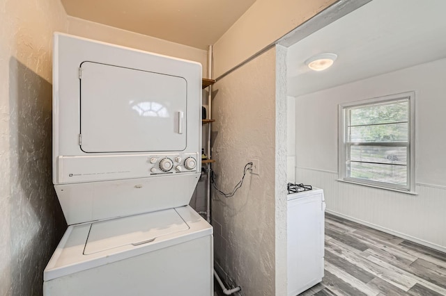 4921 Fremont Ave N, Minneapolis, MN 55430 - laundry area featuring estacked washer and dryer, light wood-style flooring, a wainscoted wall, and a textured wall