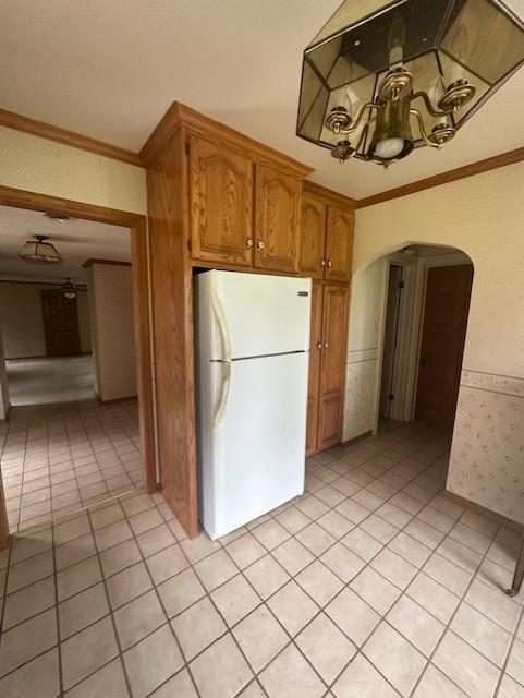 700 Oakland Pl NE, Austin, MN 55912 - kitchen with freestanding refrigerator, arched walkways, crown molding, a chandelier, and wainscoting