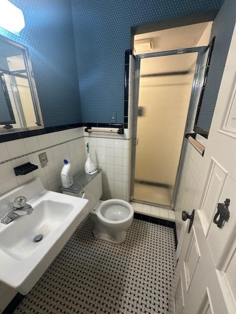 700 Oakland Pl NE, Austin, MN 55912 - full bath featuring toilet, a sink, tile walls, a stall shower, and a wainscoted wall