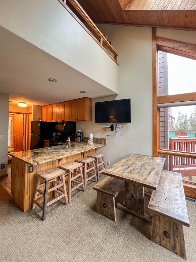 529 Moose Mountain Dr, Lutsen Twp, MN 55615 - kitchen featuring a peninsula, light carpet, a kitchen bar, black appliances, and brown cabinets
