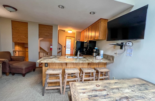 529 Moose Mountain Dr, Lutsen Twp, MN 55615 - kitchen with a peninsula, a sink, freestanding refrigerator, a kitchen breakfast bar, and light stone countertops