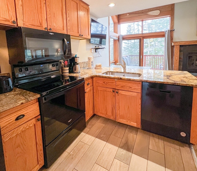529 Moose Mountain Dr, Lutsen Twp, MN 55615 - kitchen with black appliances, a sink, light wood-style flooring, a peninsula, and light stone countertops