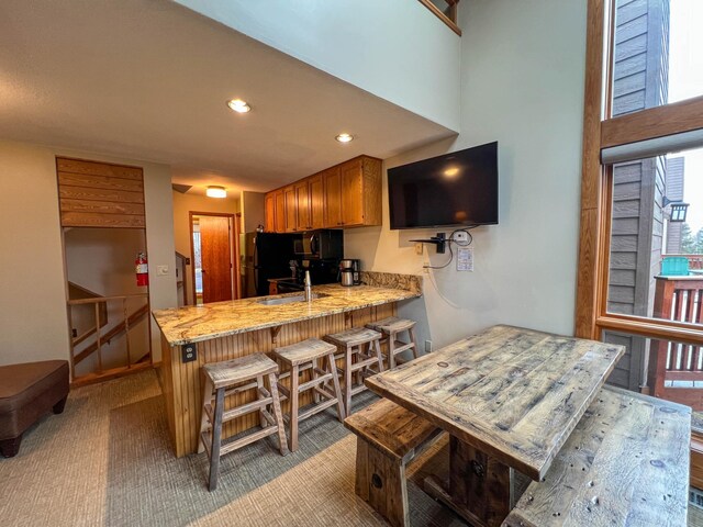 529 Moose Mountain Dr, Lutsen Twp, MN 55615 - kitchen with black microwave, a peninsula, recessed lighting, light stone counters, and brown cabinets