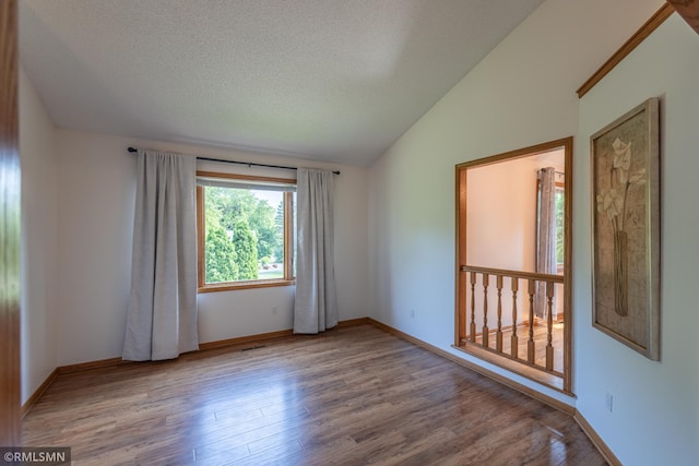 2226 Whispering Trl, Eagan, MN 55122 - spare room with wood finished floors, vaulted ceiling, baseboards, and a textured ceiling
