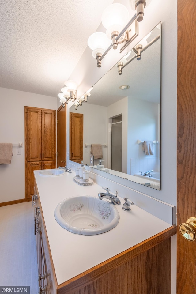 2226 Whispering Trl, Eagan, MN 55122 - bathroom featuring a chandelier, double vanity, a textured ceiling, baseboards, and a shower with door