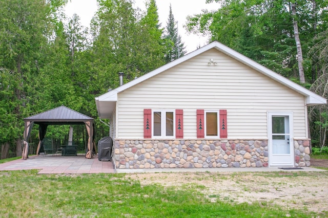 10547 Vermeil Dr NE, Deer River, MN 56636 - view of side of property featuring a gazebo, stone siding, a patio area, a detached carport, and a yard