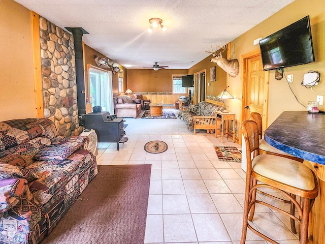10547 Vermeil Dr NE, Deer River, MN 56636 - living room featuring a ceiling fan, light tile patterned floors, a wood stove, and a textured ceiling