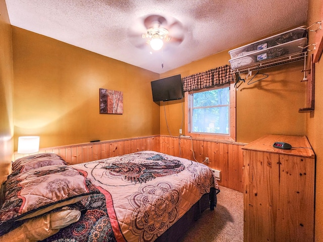 10547 Vermeil Dr NE, Deer River, MN 56636 - carpeted bedroom with a textured ceiling, wooden walls, wainscoting, and a ceiling fan