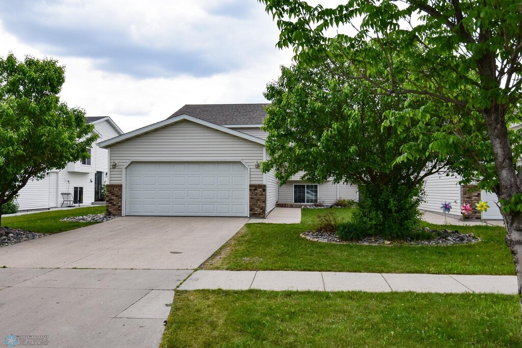 917 11th St W, West Fargo, ND 58078 - view of front of property featuring concrete driveway, a garage, a front yard, and brick siding