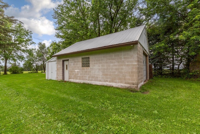 51343 20th Ave, Kenyon Twp, MN 55946 - view of side of home featuring concrete block siding, a yard, a metal roof, and an outbuilding
