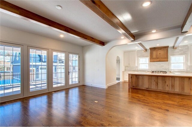 TBB403 College St, Northfield, MN 55057 - kitchen featuring arched walkways, backsplash, beam ceiling, dark wood-style floors, and baseboards