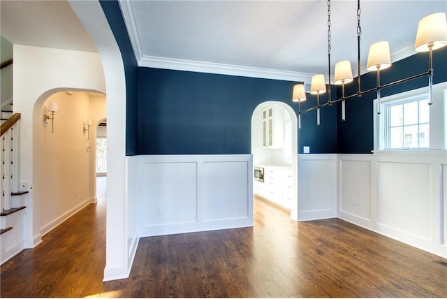 TBB403 College St, Northfield, MN 55057 - unfurnished dining area featuring arched walkways, a decorative wall, stairs, wainscoting, and wood finished floors