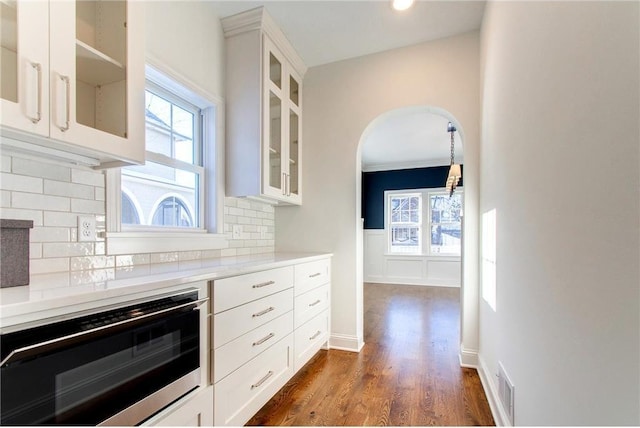 TBB403 College St, Northfield, MN 55057 - kitchen with arched walkways, light countertops, tasteful backsplash, glass insert cabinets, and recessed lighting