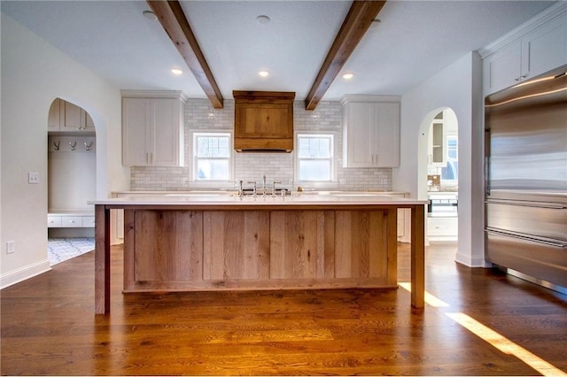 TBB403 College St, Northfield, MN 55057 - kitchen featuring stainless steel built in fridge, arched walkways, decorative backsplash, white cabinetry, and beam ceiling