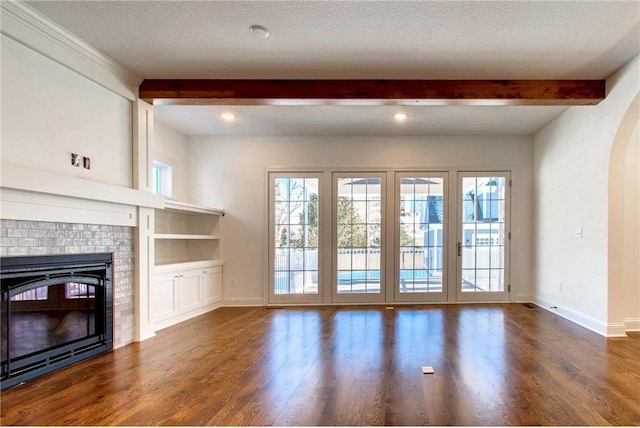 TBB403 College St, Northfield, MN 55057 - unfurnished living room featuring a fireplace, beamed ceiling, wood finished floors, baseboards, and arched walkways