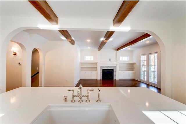 TBB403 College St, Northfield, MN 55057 - kitchen featuring beamed ceiling, open floor plan, a sink, light countertops, and a fireplace