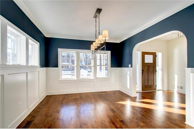 TBB403 College St, Northfield, MN 55057 - unfurnished dining area featuring arched walkways, wood finished floors, a wainscoted wall, a decorative wall, and a chandelier
