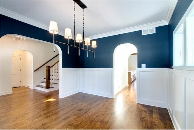 TBB403 College St, Northfield, MN 55057 - spare room featuring arched walkways, a decorative wall, crown molding, wainscoting, and wood finished floors