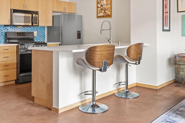 406 Wacouta St Unit 601, Saint Paul, MN 55101 - kitchen featuring appliances with stainless steel finishes, finished concrete flooring, baseboards, a kitchen bar, and light countertops