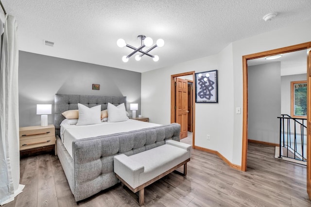 11260 Hidden Oaks Ct N, Champlin, MN 55316 - bedroom featuring a chandelier, light wood-type flooring, a textured ceiling, and baseboards