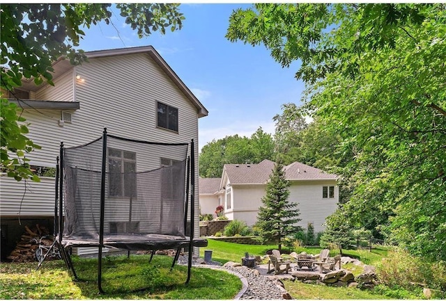 11260 Hidden Oaks Ct N, Champlin, MN 55316 - back of house featuring a trampoline, a fire pit, and a lawn