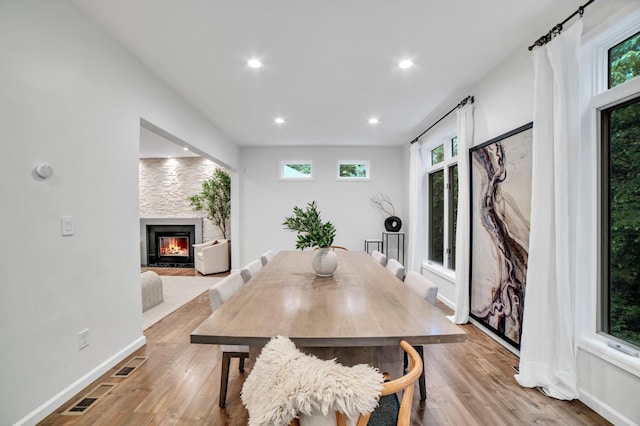 11260 Hidden Oaks Ct N, Champlin, MN 55316 - dining area with a warm lit fireplace, light wood-style flooring, recessed lighting, and baseboards