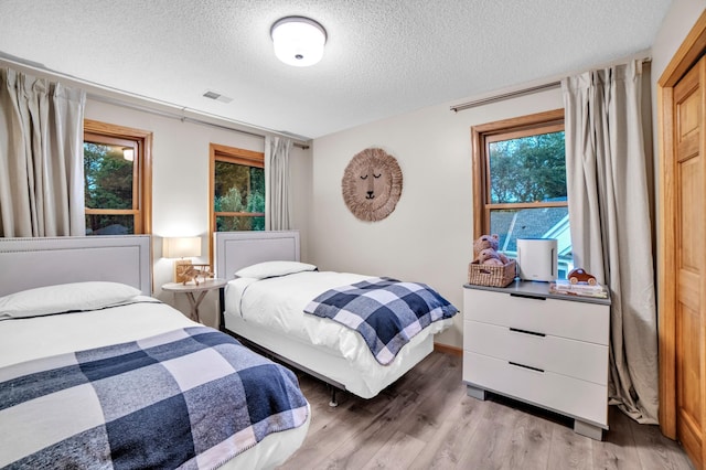 11260 Hidden Oaks Ct N, Champlin, MN 55316 - bedroom featuring a textured ceiling, multiple windows, and light wood finished floors