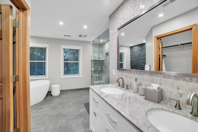 11260 Hidden Oaks Ct N, Champlin, MN 55316 - full bath with double vanity, a freestanding tub, tasteful backsplash, baseboards, and a spacious closet